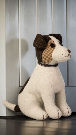 Dora Designs Jack Russell dog doorstop beside a painted wooden door