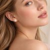 Model wearing naturally rose-pink freshwater pearl stud earrings set in 14ct yellow gold.