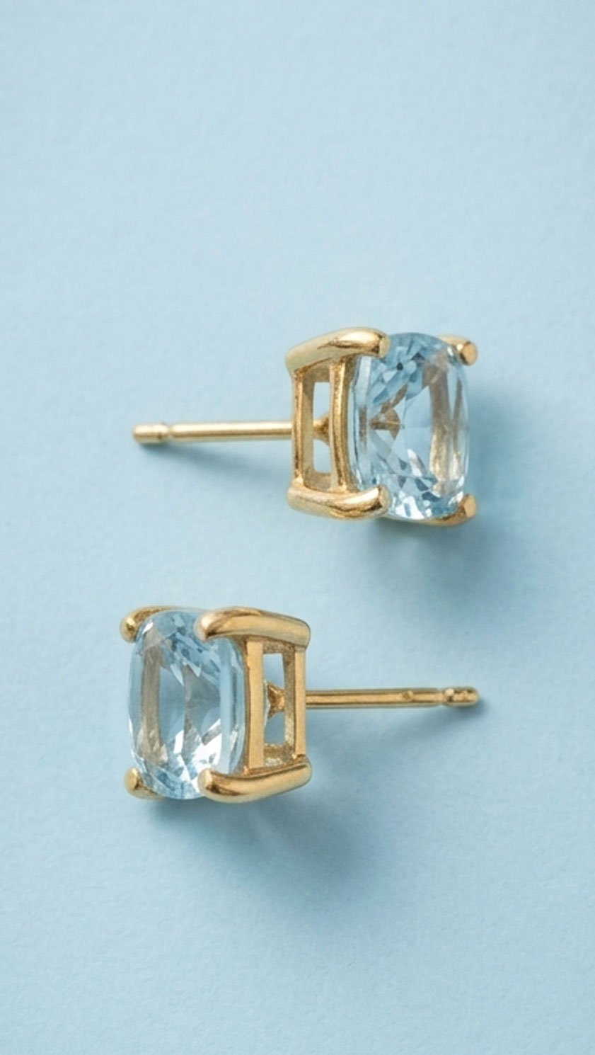8ct gold 7mm cushion cut aquamarine stud earrings on blue background showing clarity and setting