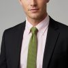 Man wearing olive green knitted silk tie with dark jacket and pink shirt