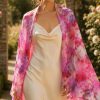Woman wearing the Blush Garden pure silk chiffon stole in pink floral design over an ivory silk dress in a rose garden.