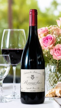 Bottle of Domaine Dupeuble Château des Pertonnières Beaujolais 2023 on a table with wine glasses and pink roses