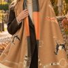 La Chasse equestrian scarf in camel, horses and tack, worn over a coat.